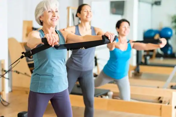 Toning Arms After 60: Empowering Womens Fitness Through Effective Weight Training 2 older woman doing weight training Llanelli and resistance in the gym to tone upper arms