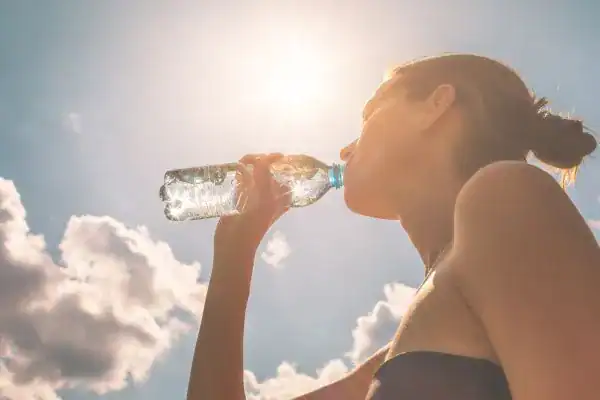 Hydration: The Secret Ingredient for a Toned Stomach and Enhanced Fitness 3 Image of woman drinking water to hydrate Llanelli after run.
