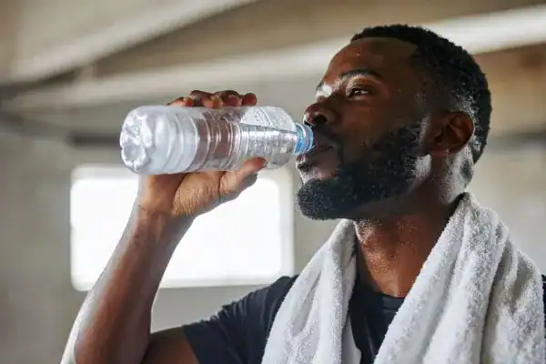 Image of man drinking water to improve hydration Llanelli after work out.